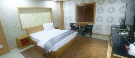 A bedroom with a bed, a small table, and a chair.