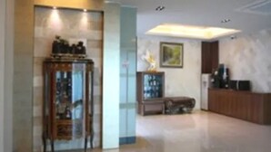 A spacious living area with a wooden cabinet, a glass display case, and a painting on the wall. - Goryeo Hotel (Andong)