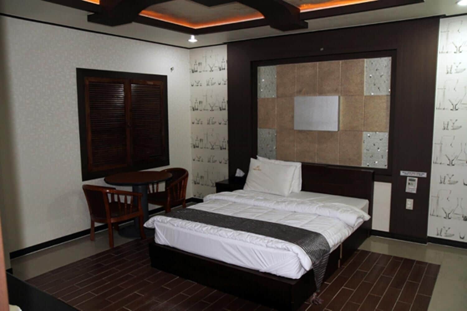 A hotel room with a large bed, a desk, and a chair.