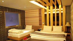 A hotel room with two beds, a large window, and a wooden ceiling structure. - Goryeo Hotel (Andong)