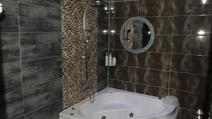 A modern bathroom with a freestanding bathtub, a shower area, and a round mirror on the wall. - Goryeo Hotel (Andong)