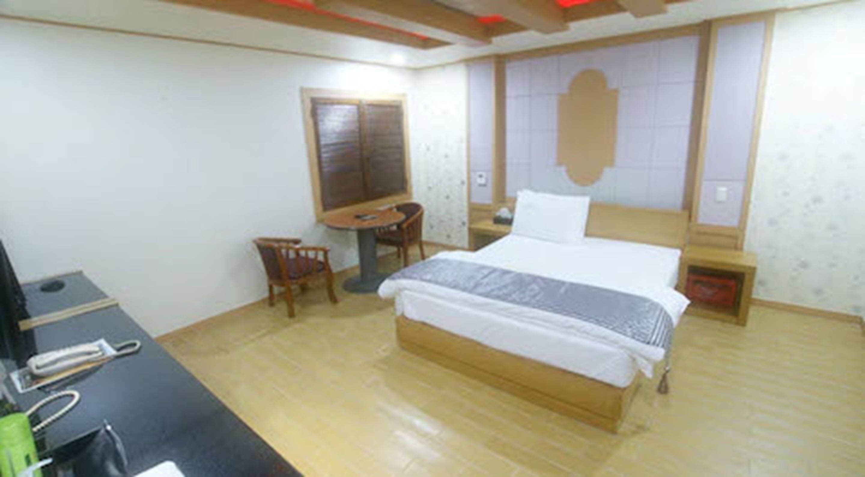 A bedroom with a bed, a desk, a chair, and a small table.
