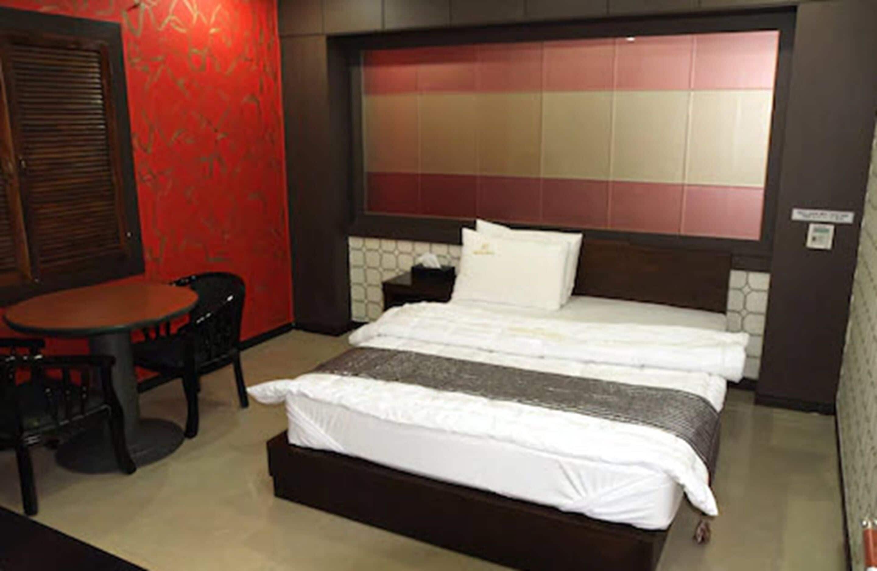 A hotel room with a bed, a small table, and a chair.
