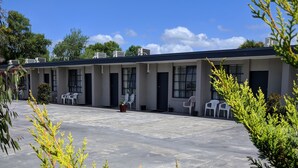 A motel with a flat roof, multiple rooms, and a paved parking area. - Beaconsfield Lodge Motel (Beaconsfield)
