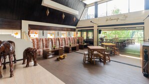 A spacious lounge area with wooden furniture, a staircase with orange decorations, and a view of the outdoors. - Driam Riverside Resort (Pasirjambu)