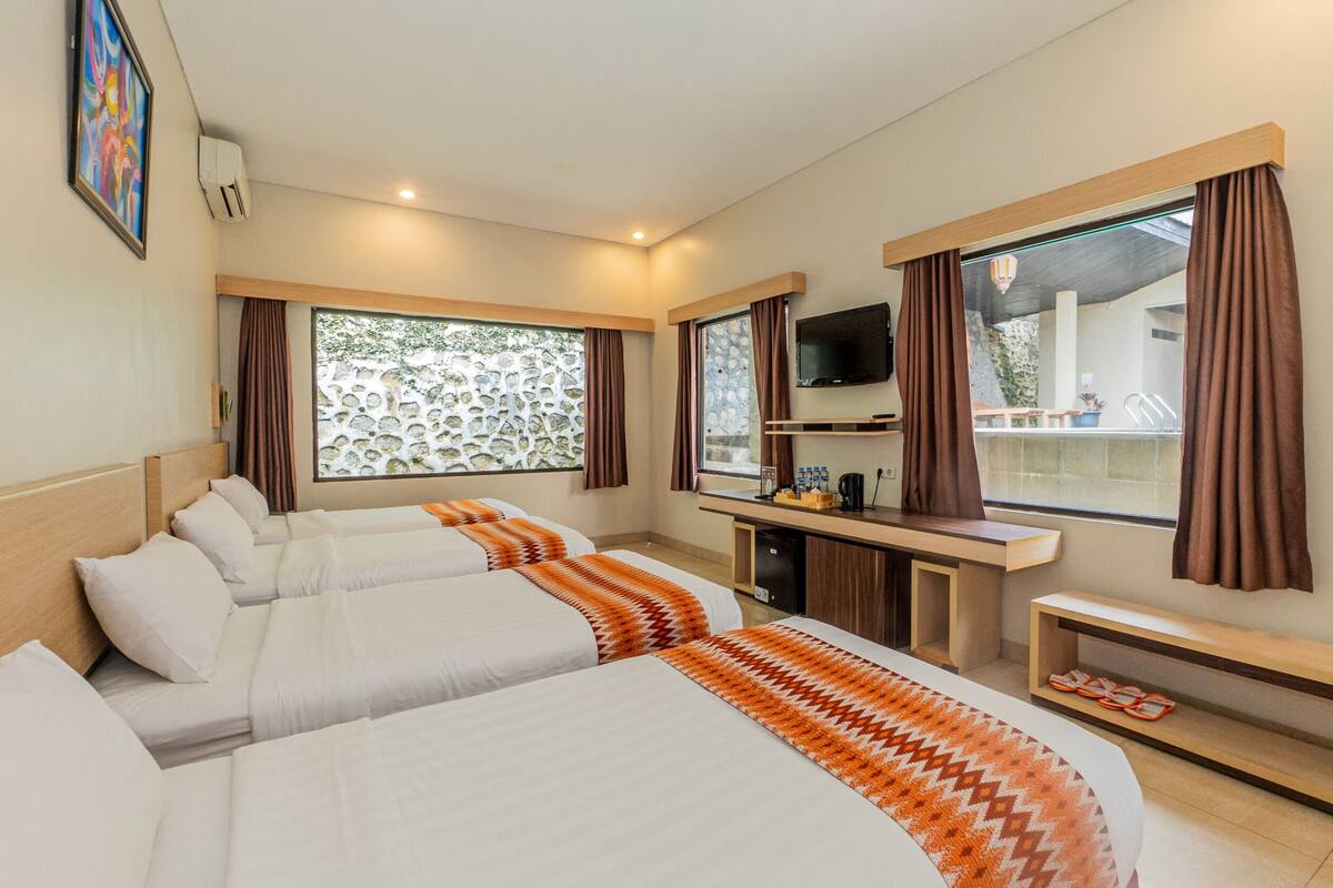 A hotel room with two beds, a TV, a desk, and a window with curtains.