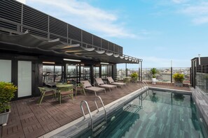 Een buitenzwembad, ligstoelen bij het zwembad