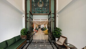 A spacious lobby with a green sofa, a round table, and a large glass entrance. - SQ HANG GAI HOTEL & SPA (Hanoi)