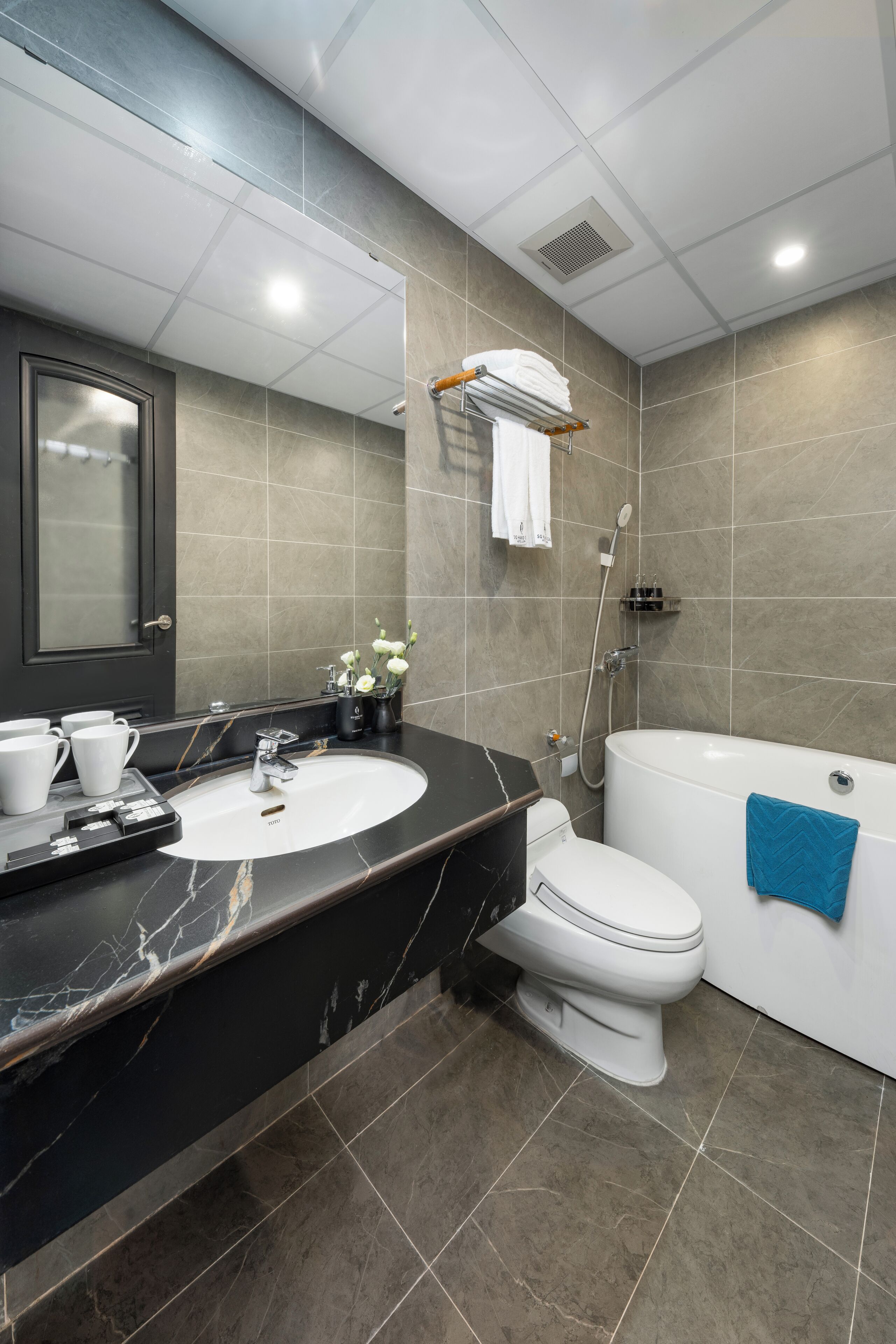 A modern bathroom with a marble sink, a toilet, and a bathtub.