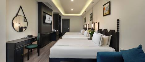 A hotel room with a desk, two beds, a sofa, and a mirror.