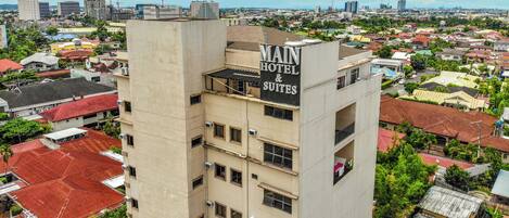 Un hotel de varios pisos con un letrero que dice 'MAIN HOTEL & SUITES'.