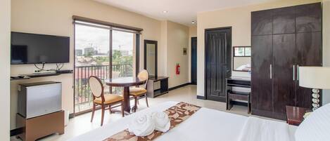 A hotel room with a bed, a TV, a desk, a chair, and a balcony with a view.