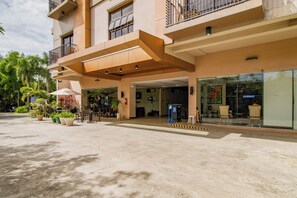 A hotel entrance with a covered walkway, outdoor seating, and potted plants. - Main Hotel and Suites Cebu (Cebu City)