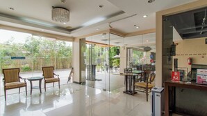 Un hall d’hôtel avec des portes vitrées donnant sur un espace extérieur, un comptoir d’accueil et des espaces aménagés pour s’asseoir.
