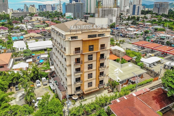Un hotel de varios pisos con balcones, rodeado por una zona urbana densa con diversos edificios y zonas verdes.