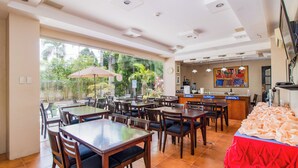 Un restaurant doté de nombreuses tables et chaises, d’un comptoir et d’une grande fenêtre donnant sur un espace verdoyant.