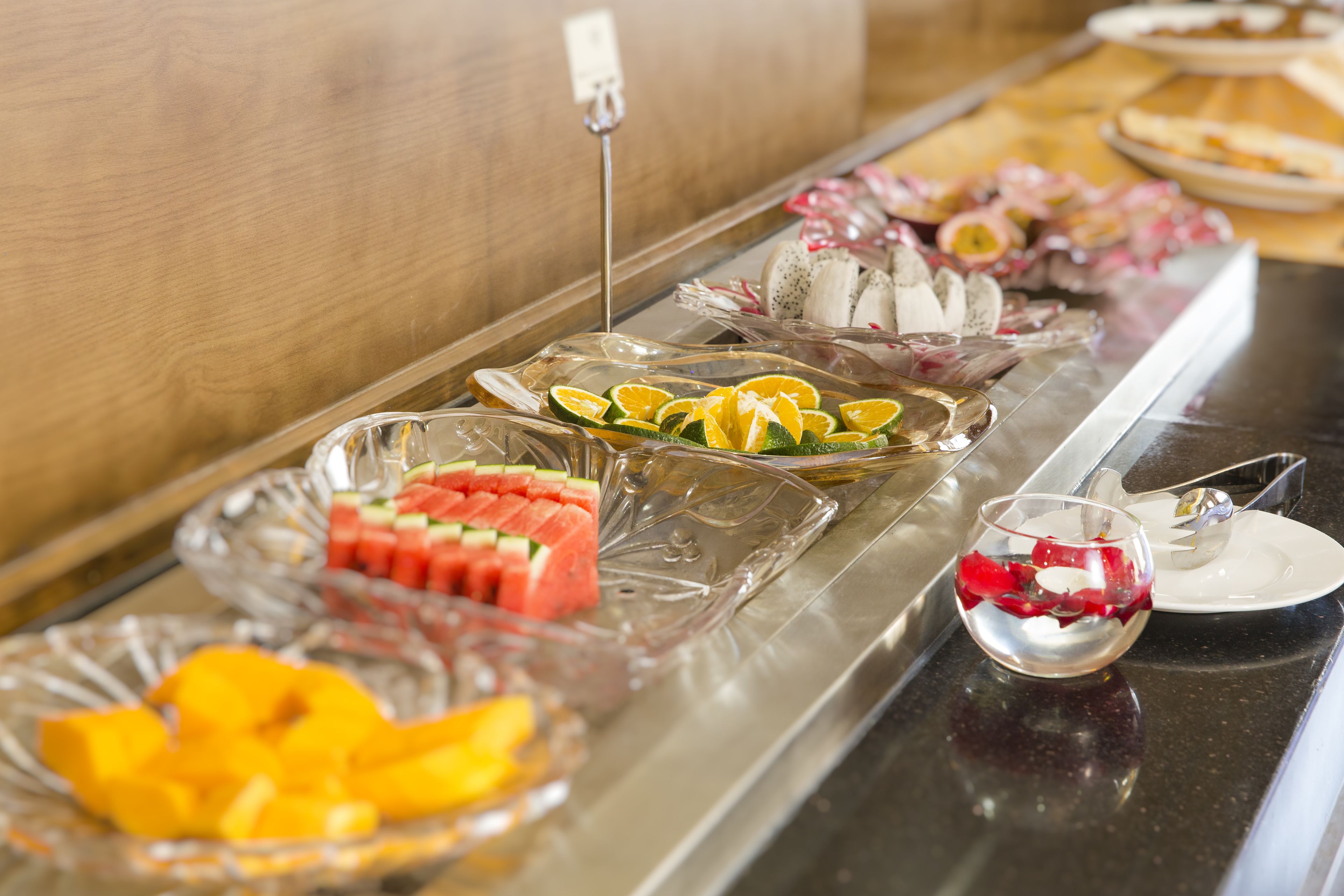 A buffet with various fruits and a small glass bowl.