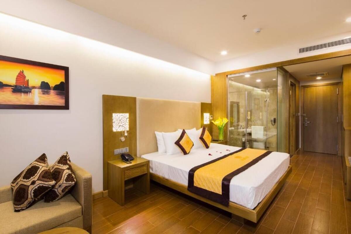 A hotel room with a bed, bedside table, and a glass shower enclosure.