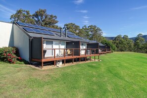 A modern building with solar panels, a wooden deck, and a well-maintained lawn. - Wine Country Villas (Pokolbin)