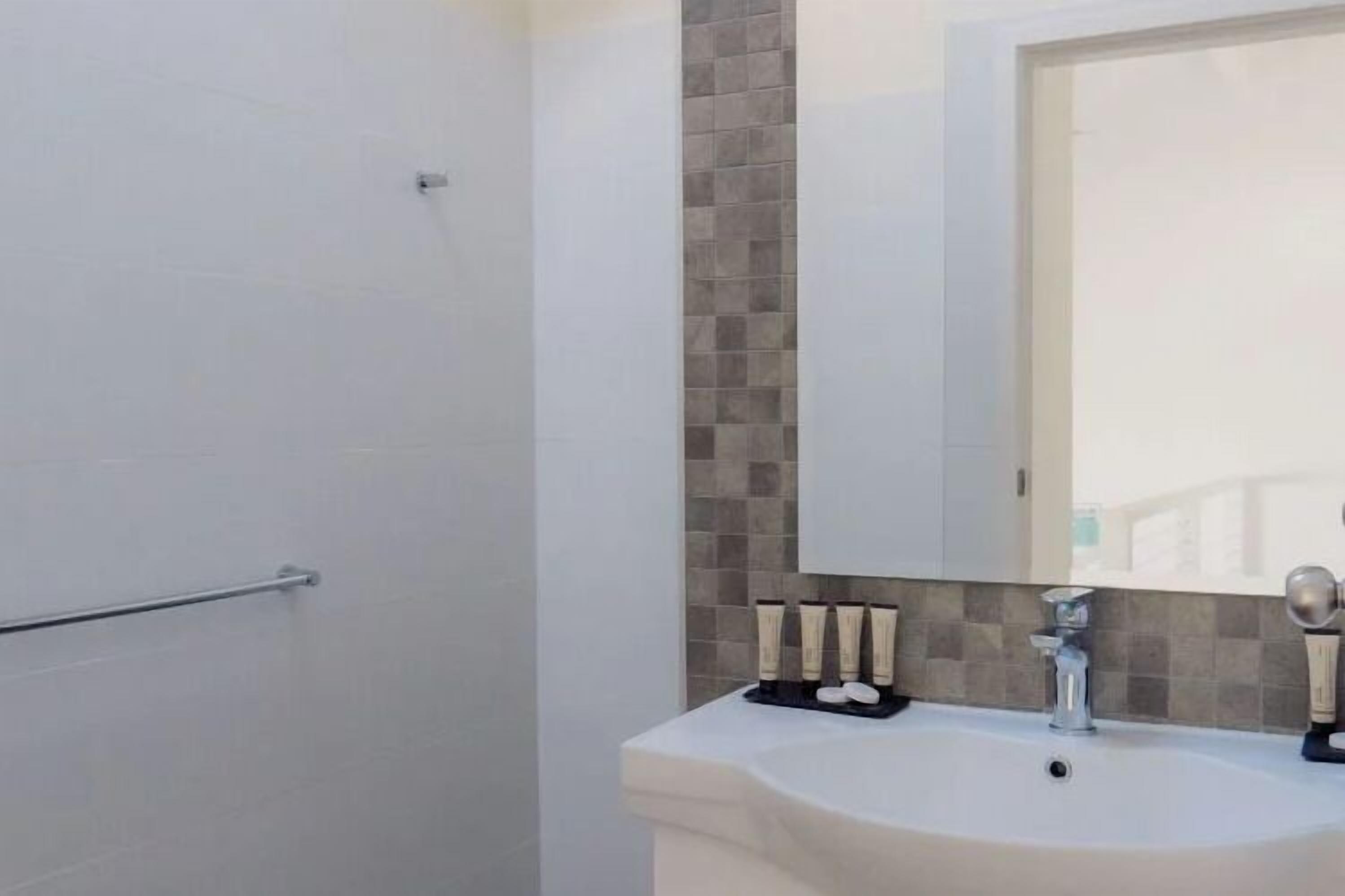 Une salle de bain avec un lavabo blanc, un miroir et des articles de toilette.