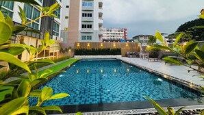 A swimming pool with a tiled floor, surrounded by greenery and modern buildings. - Three Seasons Bangkok (Bangkok)