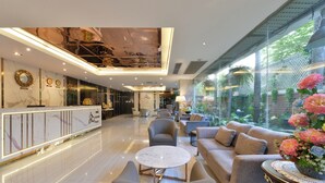 A spacious lobby with a reception desk, seating area, and a glass wall offering a view of a lush garden. - Three Seasons Bangkok (Bangkok)