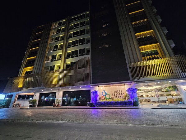 A multi-story hotel with a modern facade, illuminated windows, and a landscaped entrance area. - Three Seasons Bangkok (Bangkok)