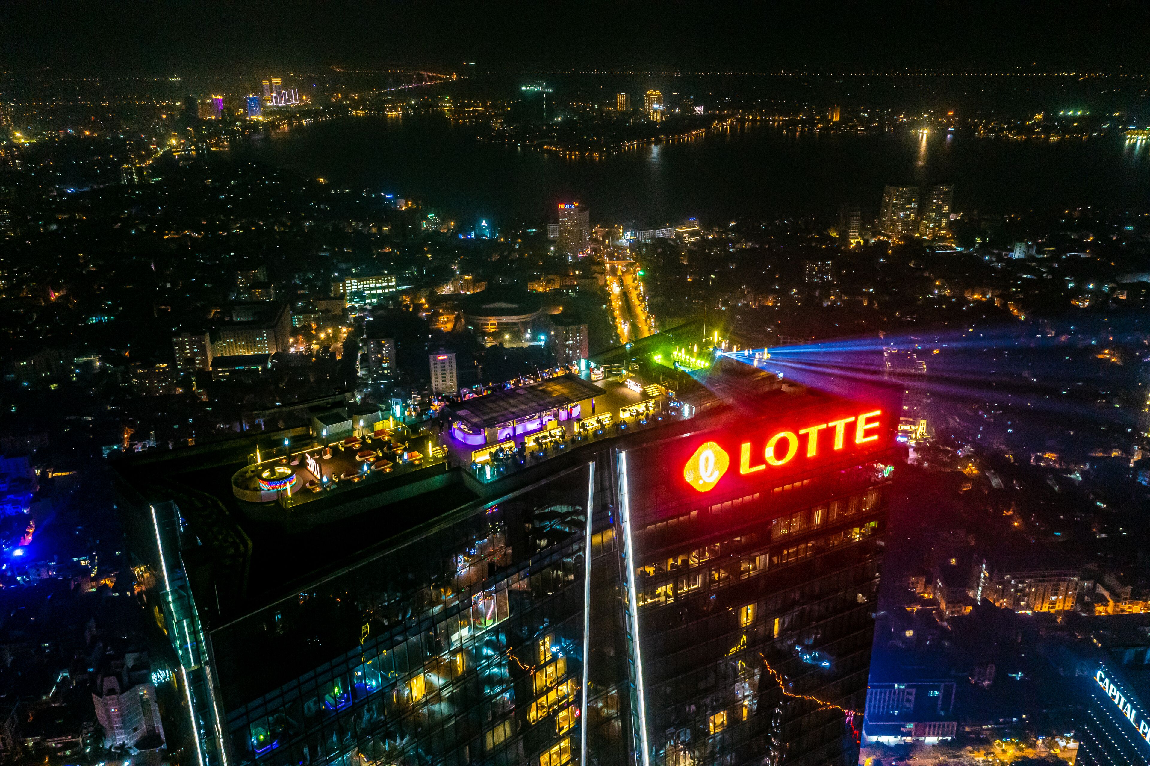 A nighttime cityscape with illuminated buildings and a prominent hotel sign.
