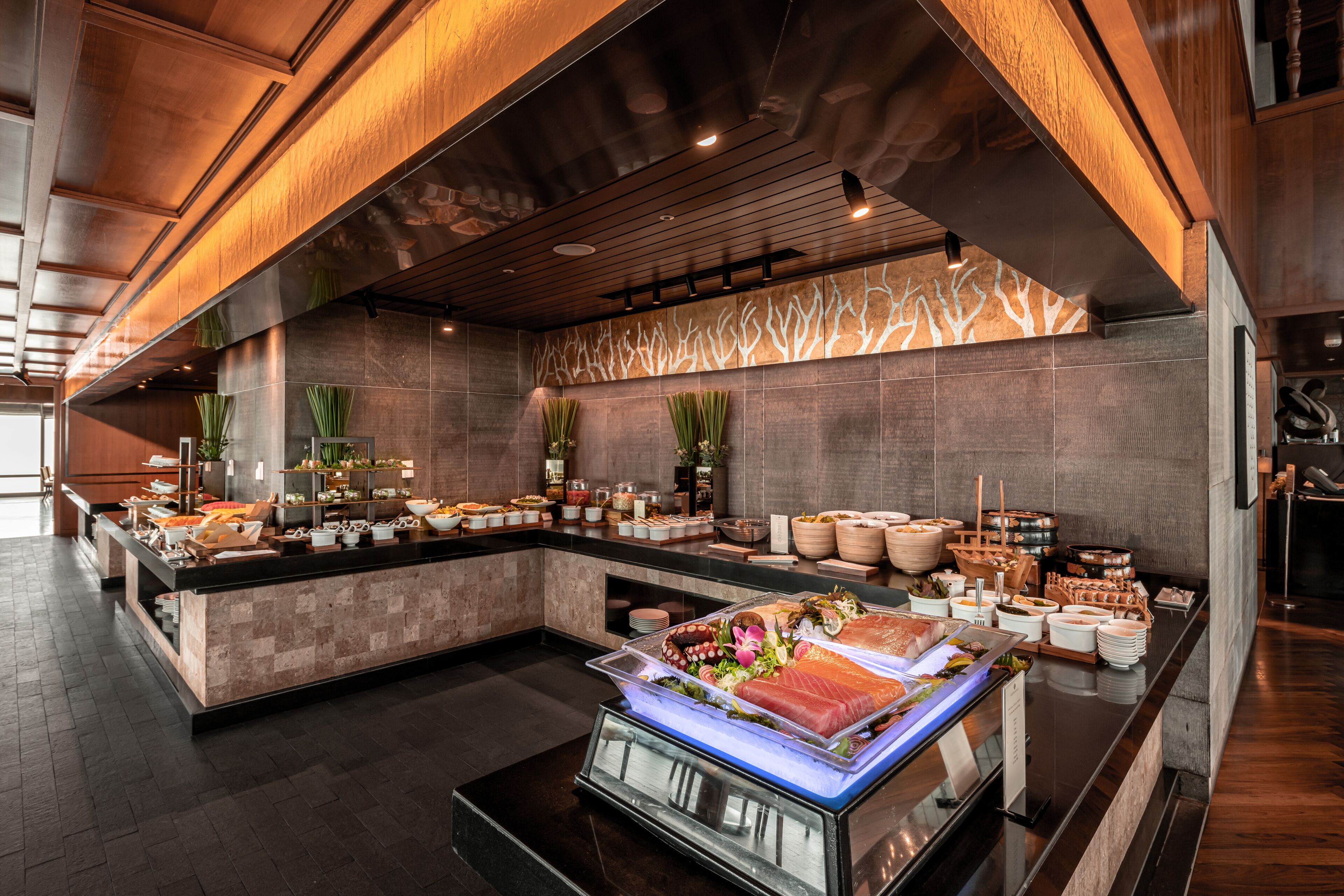 A modern buffet setup with a variety of food items and a central display of fresh produce.