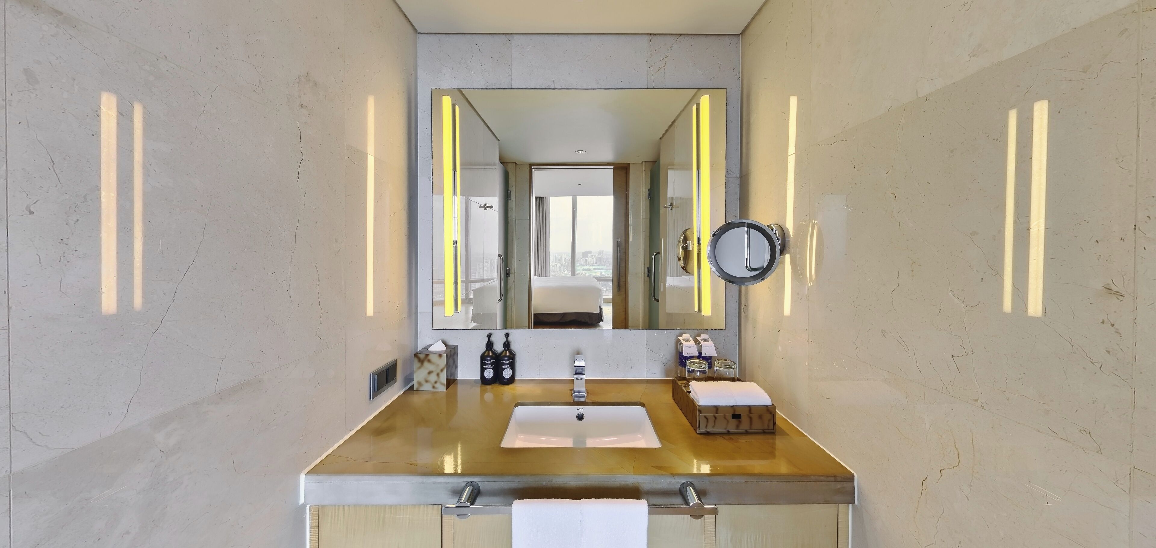 Un baño moderno con encimera de mármol, un espejo grande y un lavabo pequeño.