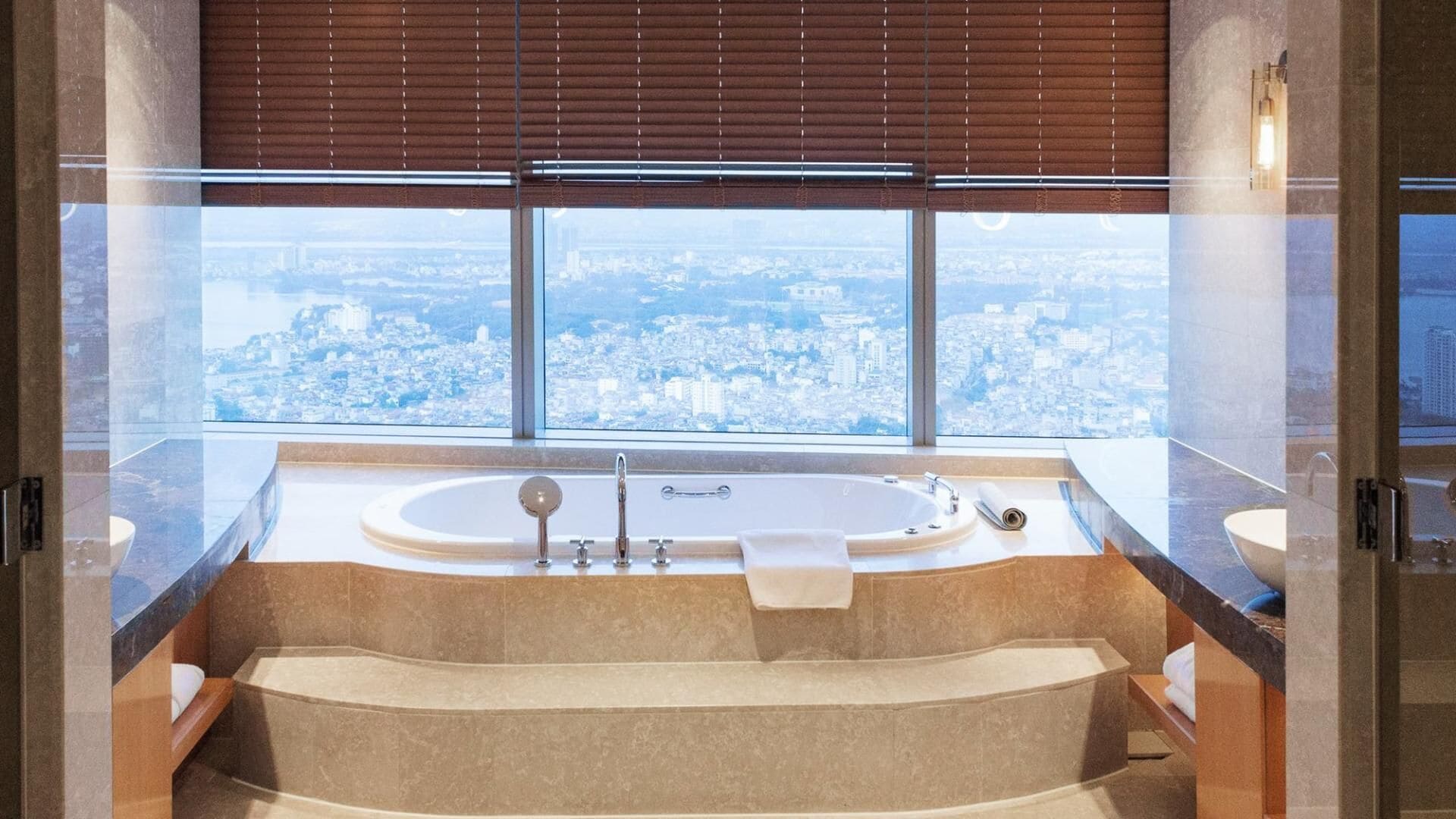Un baño moderno con una bañera grande, un lavamanos independiente y un ventanal con vistas a la ciudad.