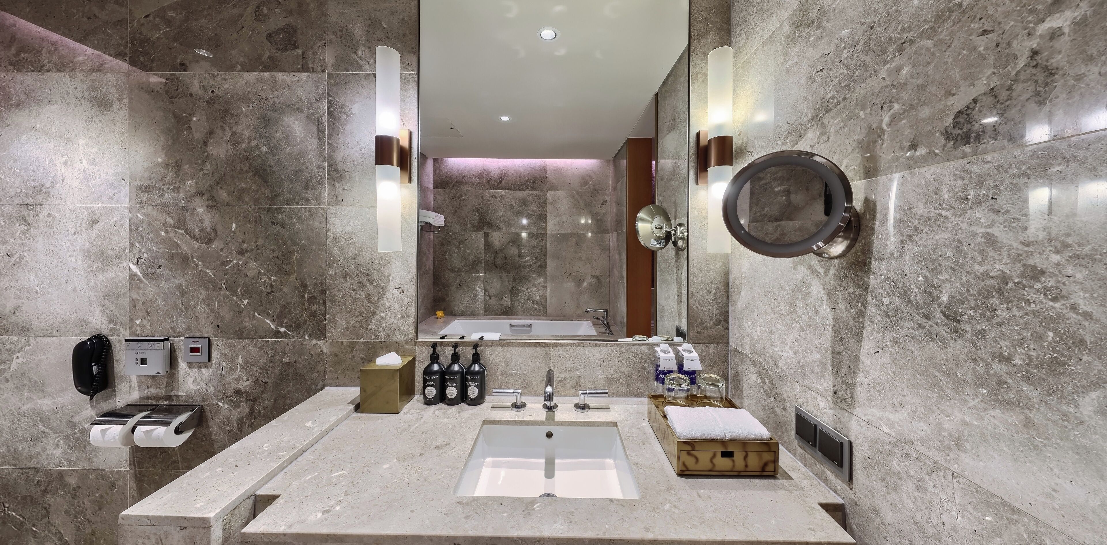 Un baño moderno con lavamanos de mármol, un espejo grande y ducha integrada.
