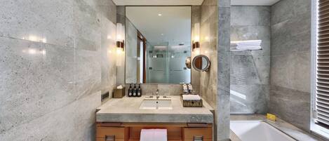 A modern bathroom with a large mirror, two sinks, a bathtub, and a vanity with drawers.