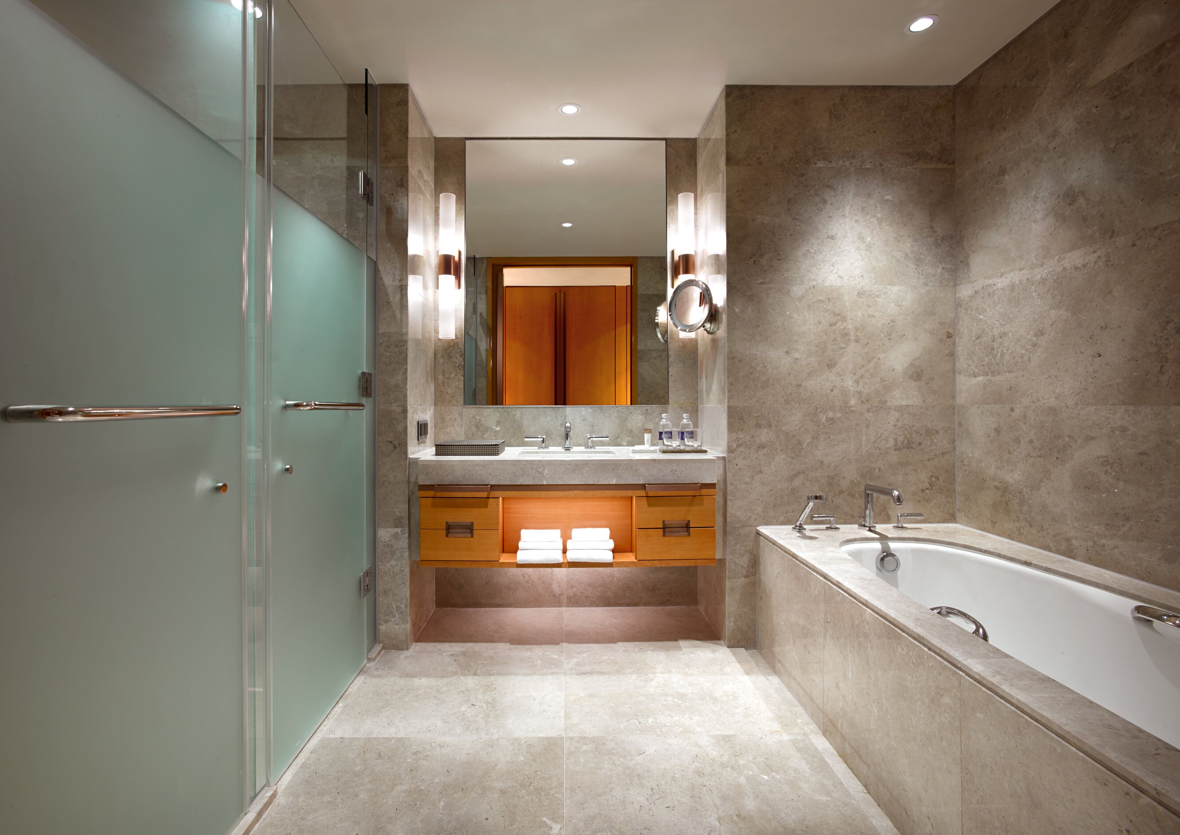 A modern bathroom with a glass shower enclosure, a freestanding bathtub, and a vanity with a mirror.