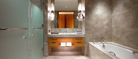 A modern bathroom with a glass shower enclosure, a freestanding bathtub, and a vanity with a mirror.