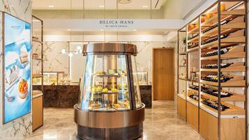 Un moderno vestíbulo de hotel con una exhibición central de postres, estanterías para vinos y un suelo de mármol.