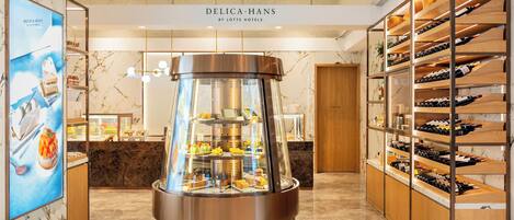 A modern hotel lobby with a central dessert display, wine racks, and a marble floor.