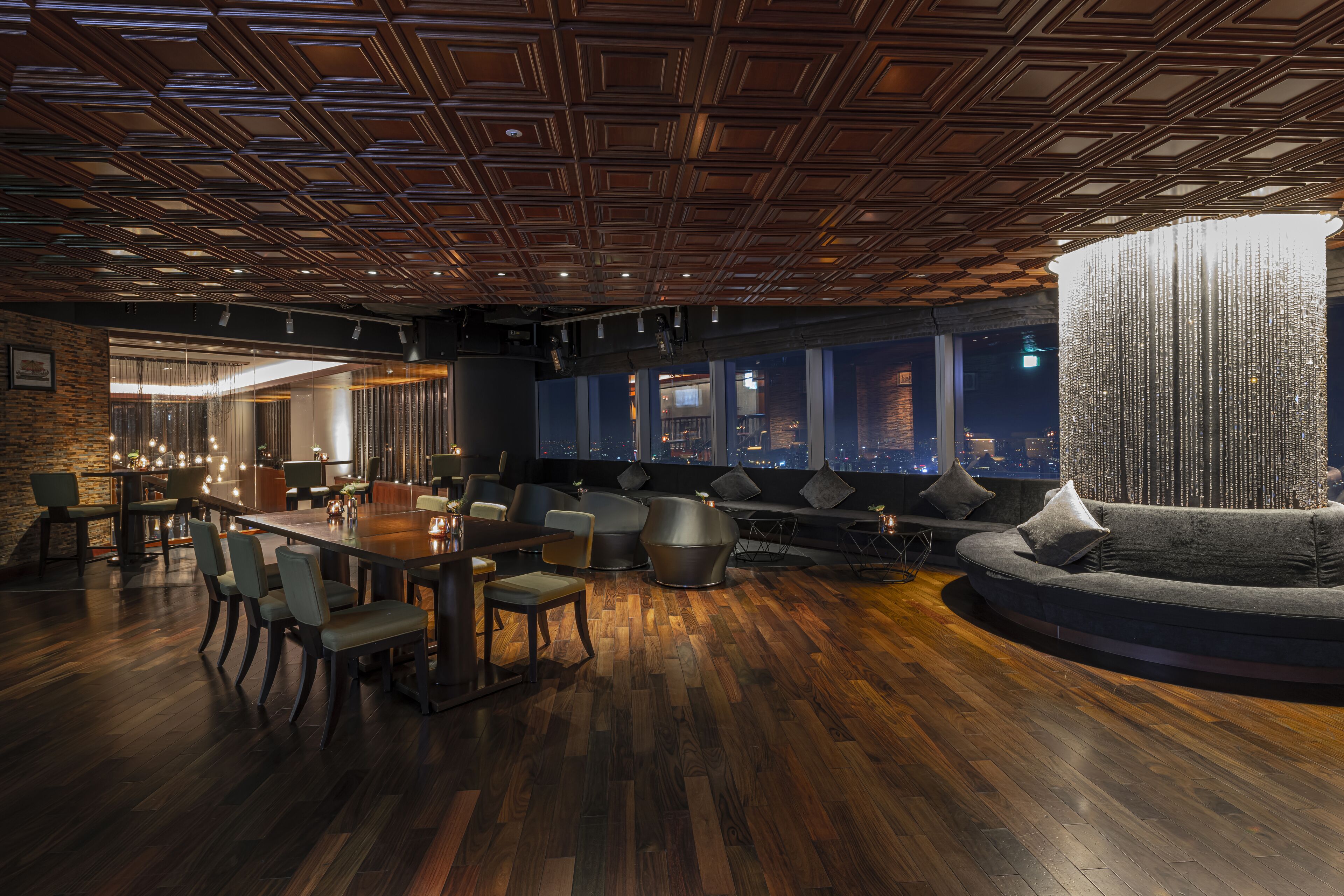 A modern interior with a wooden floor, a round dining table, and a large sofa.