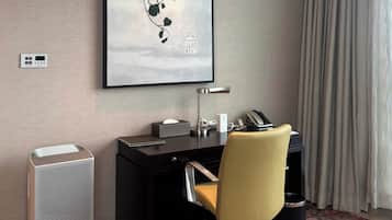 Habitación de hotel con escritorio, silla y una obra de arte enmarcada en la pared.