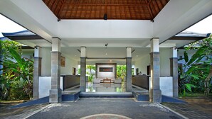A covered entrance with a central seating area, stone pillars, and a tiled floor. - The Brothers Villas Padang Padang (Pecatu)