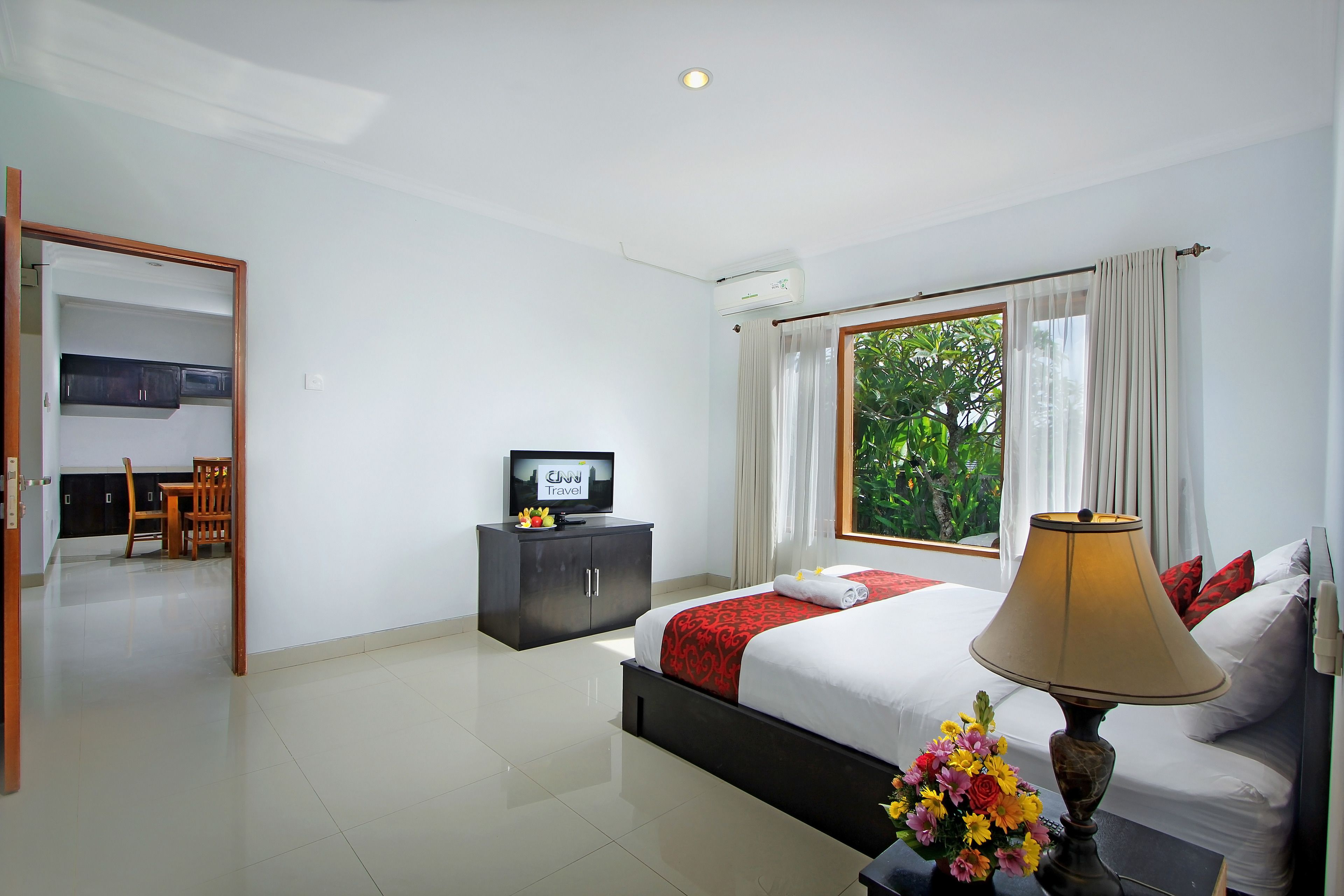 A hotel room with a bed, a TV, a desk, and a window with curtains.