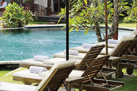 Una piscina al aire libre, sillones reclinables de piscina