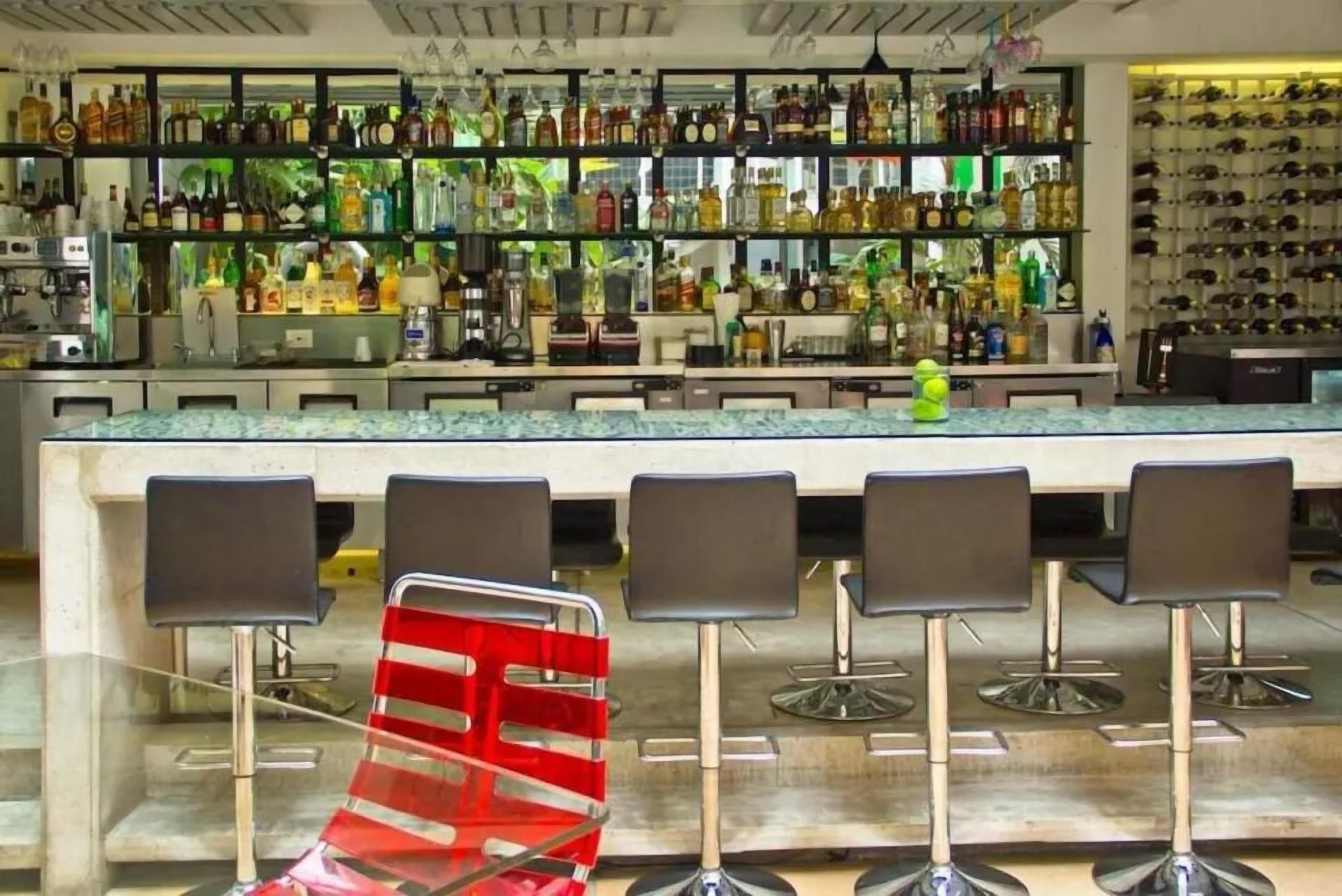 A bar area with multiple stools, shelves stocked with bottles, and a counter.