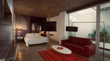 A modern hotel room with a bed, red sofa, and a TV.