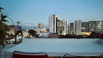 Relax in a rooftop seating area with a city view, featuring a table and two chairs.