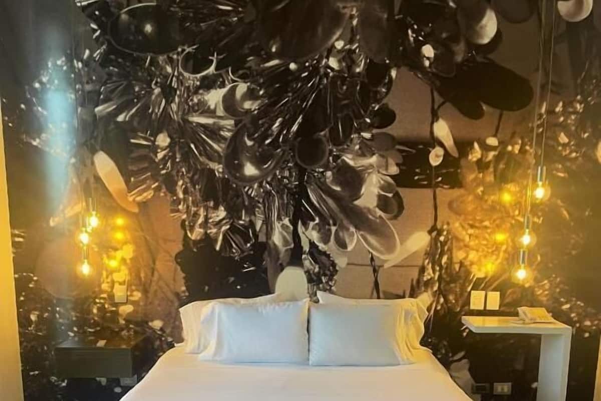 Un dormitorio moderno con una cama grande, una lámpara decorativa en el techo e iluminación ambiental.
