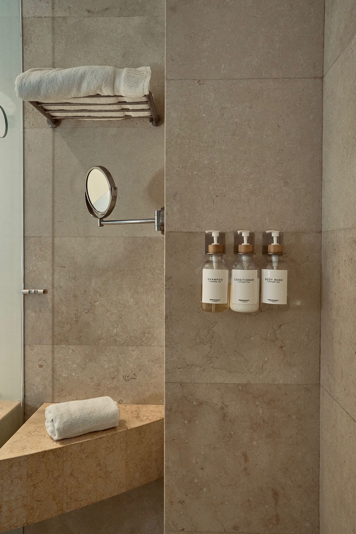 A bathroom with a towel rack, a mirror, and three bottles of toiletries.