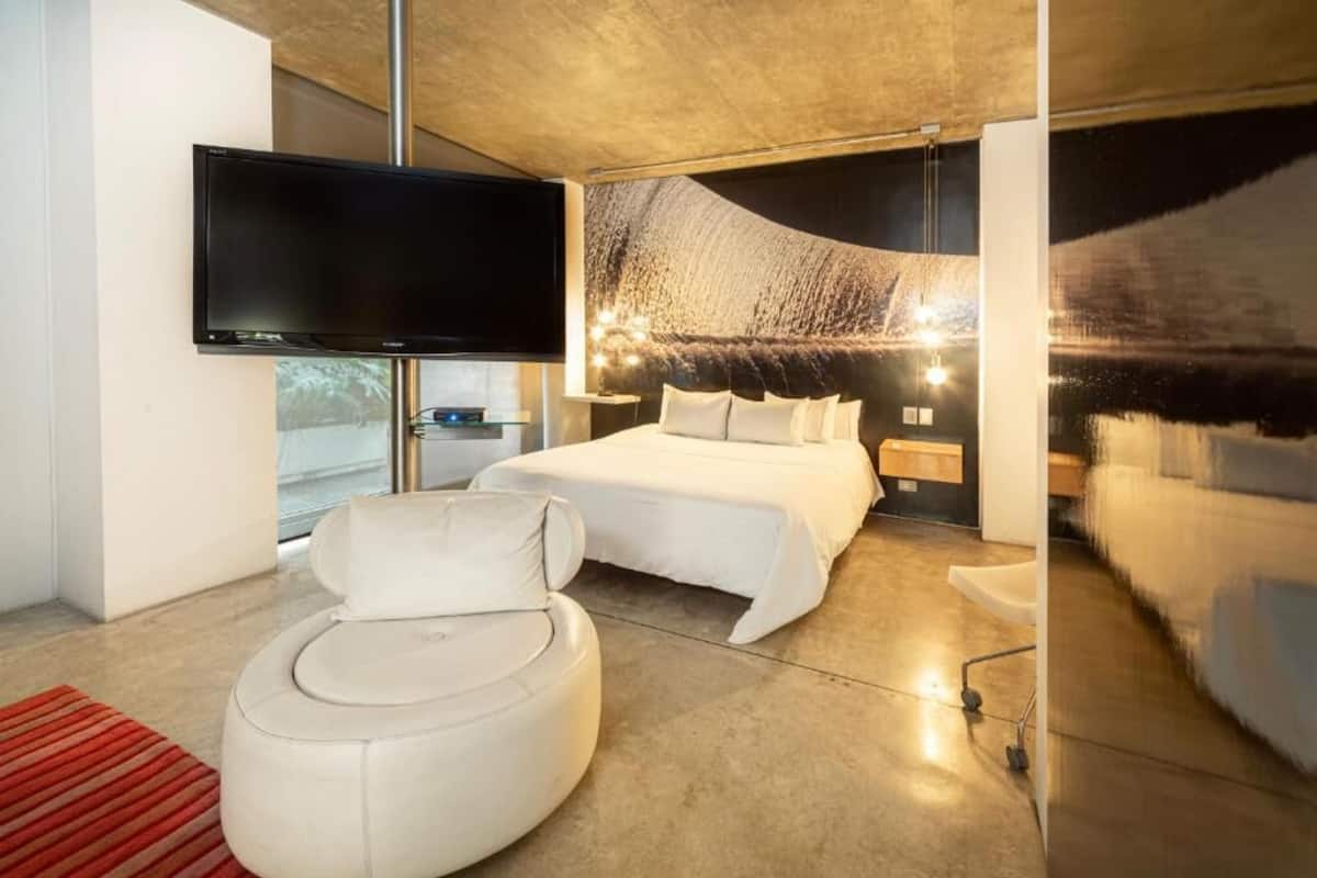 Un dormitorio moderno con una cama grande, un televisor de pantalla plana e instalación artística única en la pared.