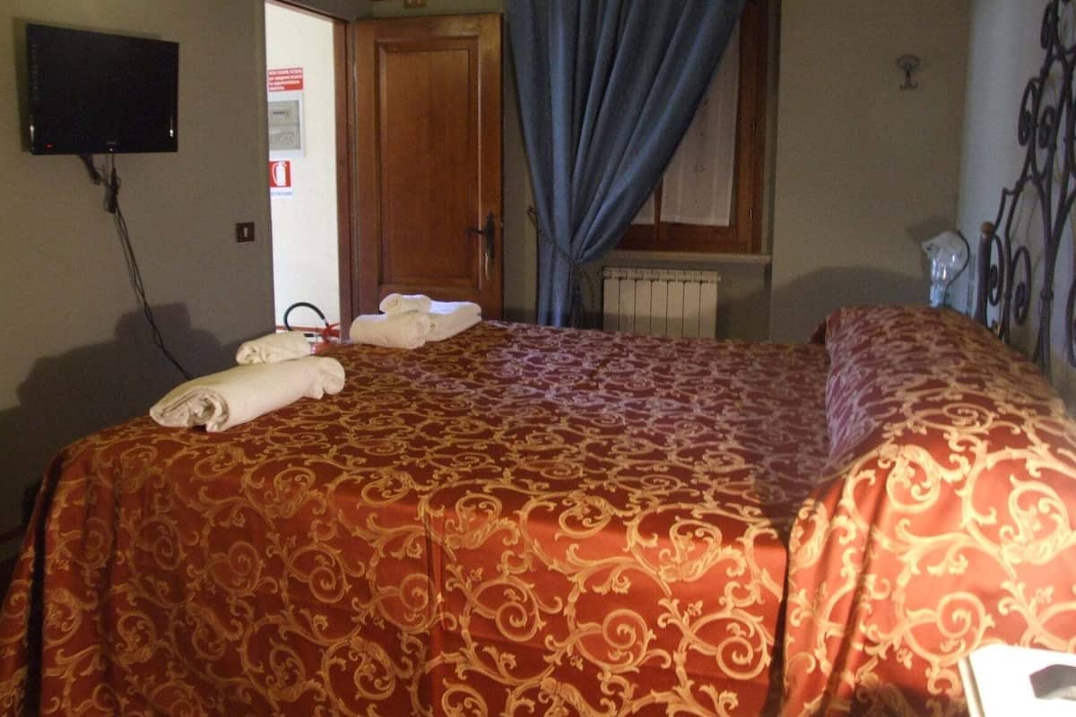 Ein Hotelzimmer mit einem Bett, einem Fernseher, einer Tür und einem Vorhangfenster.