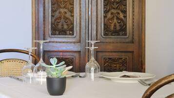 A dining table set with clear glassware, a potted plant, and a candle.